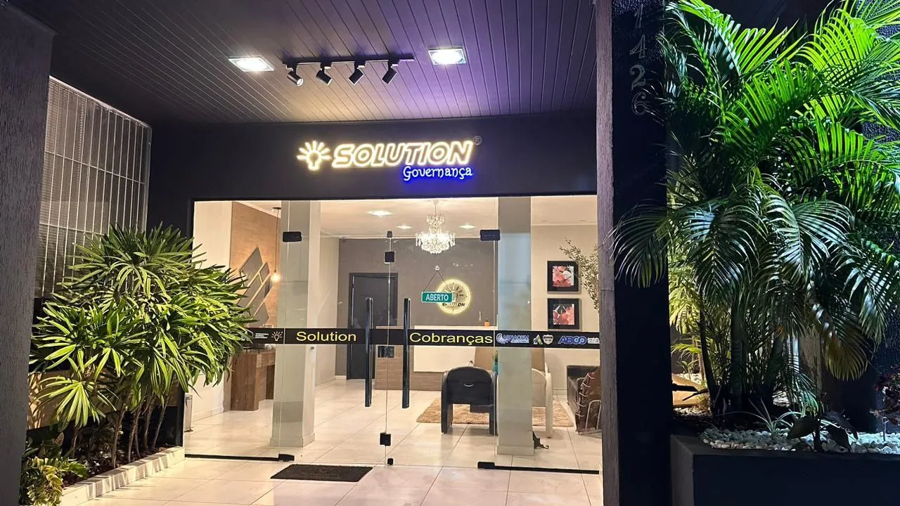 Fachada do escritório à noite, com o letreiro da Solution